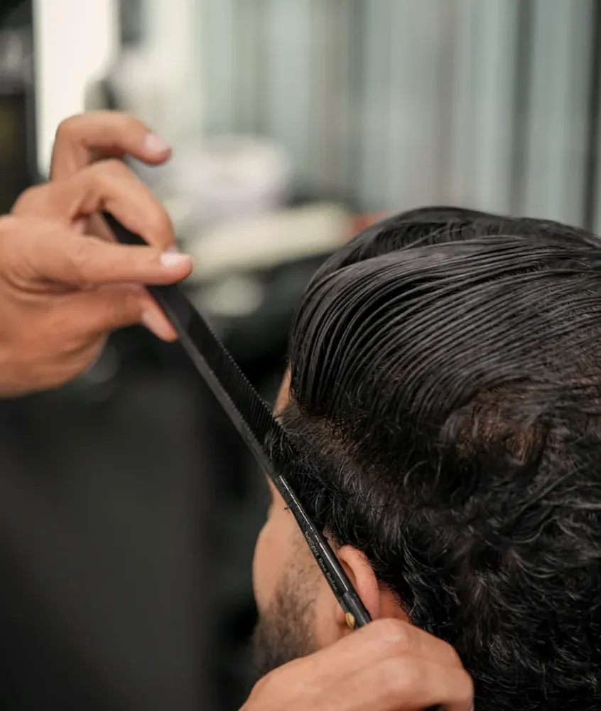 Peigne de coiffeur passé dans les cheveux d'un client pendant la coupe