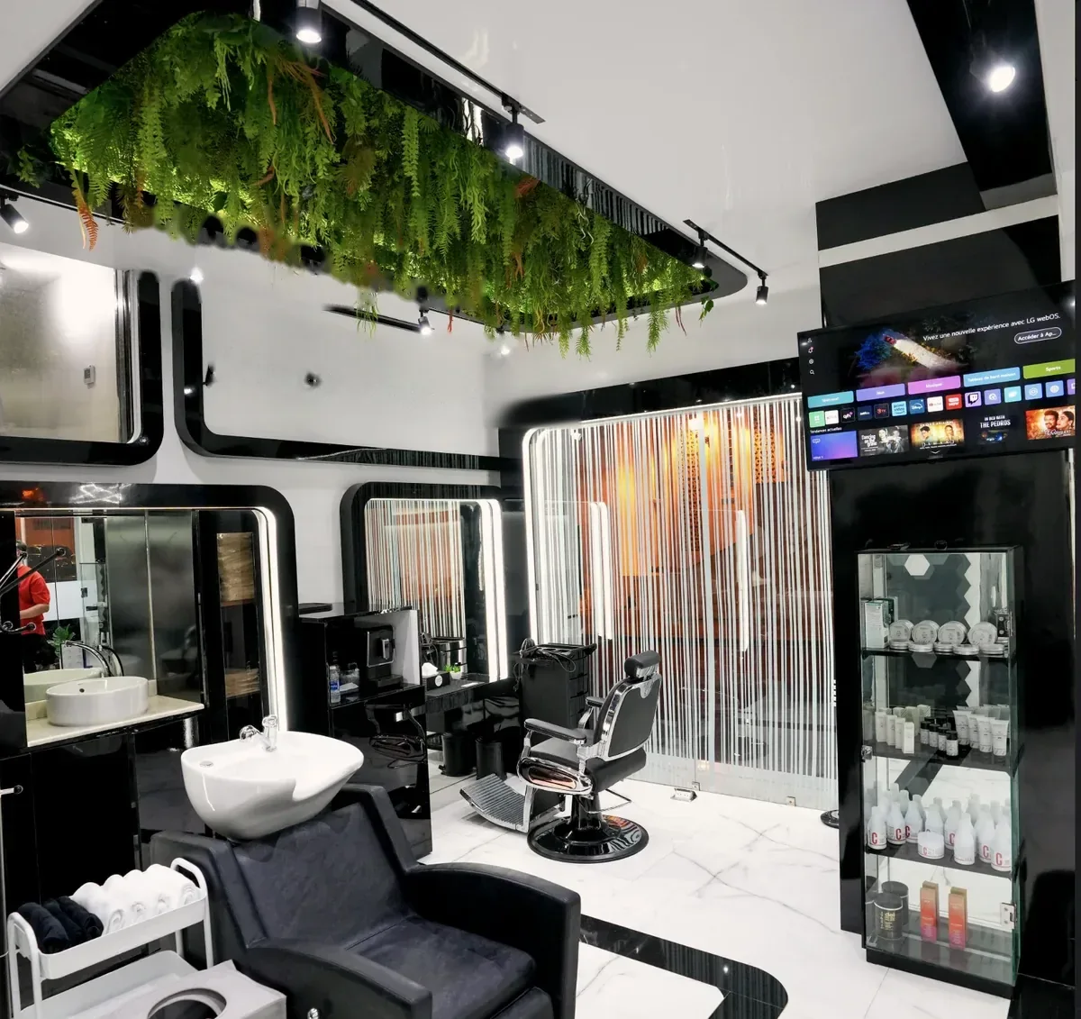 Intérieur du salon, bac de lavage, fauteuil de barbier et végétation suspendue au plafond